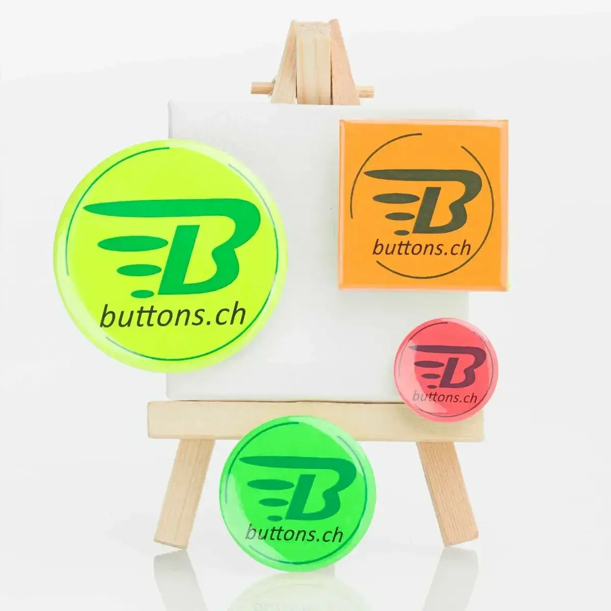 Neonbuttons in Gelb, Orange, Rot und Grün mit buttons.ch-Logo auf einer kleinen Staffelei.