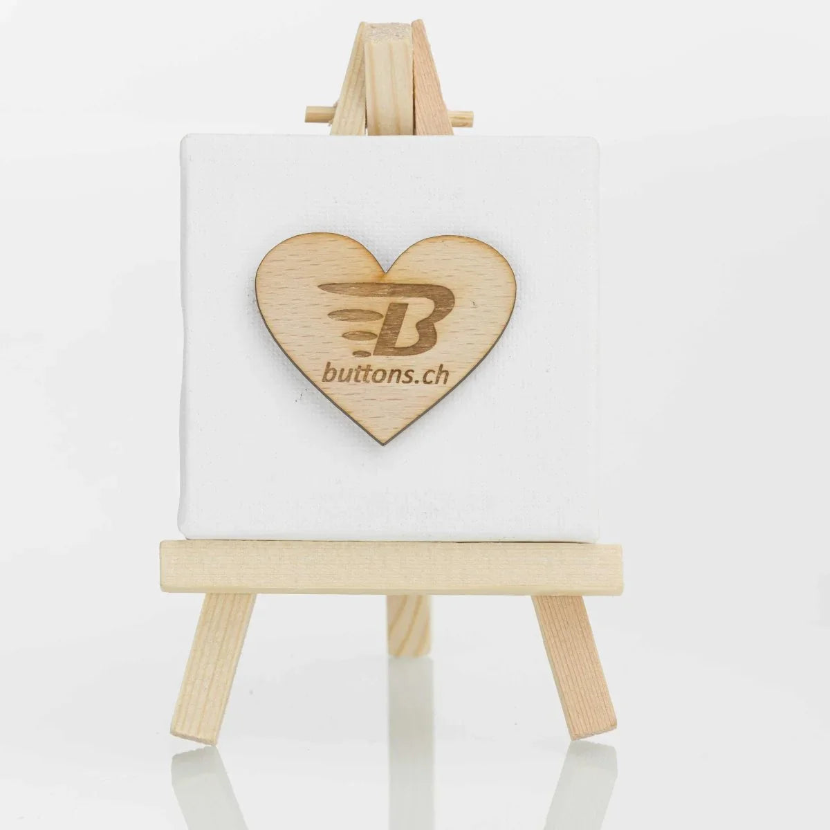 Herzförmiger Holz-Anstecker mit eingraviertem buttons.ch-Logo.