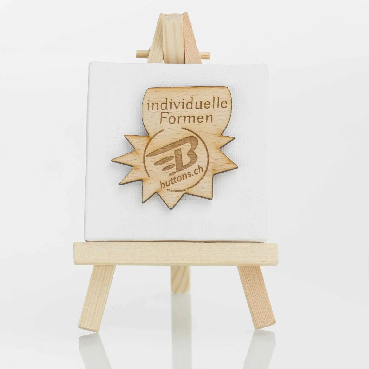 Holz-Anstecker in einer gezackten Sonderform mit buttons.ch-Logo.