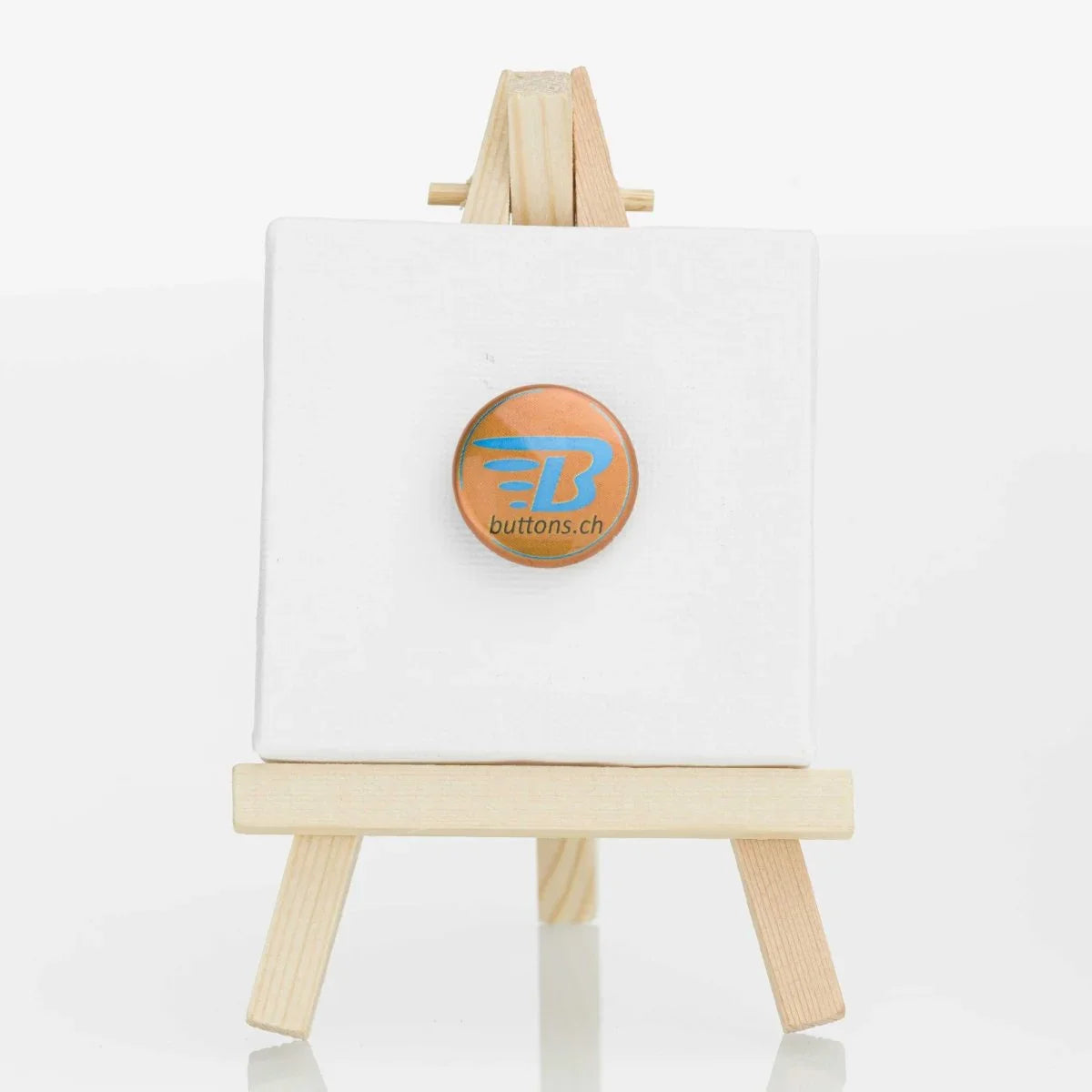 Runder Metallic-Button in Bronze, 25 mm, mit blauem buttons.ch-Logo.