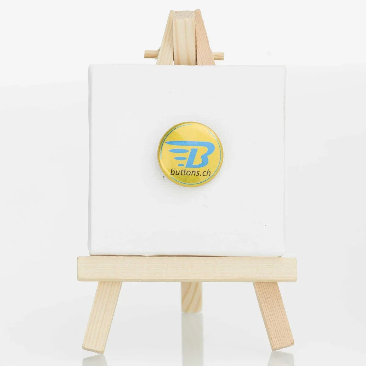 Runder Metallic-Button in Gold, 25 mm, mit blauem buttons.ch-Logo.