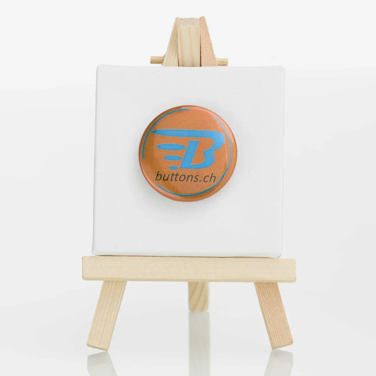 Runder Metallic-Button in Bronze, 37 mm, mit blauem buttons.ch-Logo.