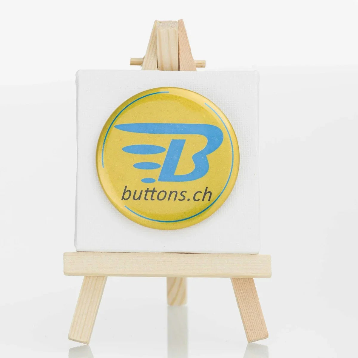 Runder Metallic-Button in Gold, 56 mm, mit blauem buttons.ch-Logo.