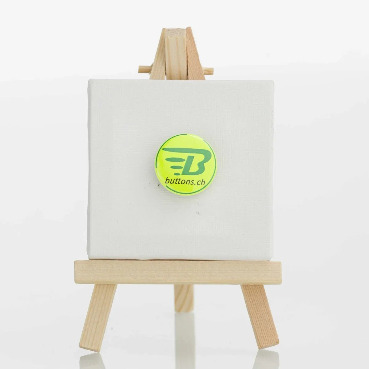 Runder Neonbutton in Neongelb, 25 mm, mit buttons.ch-Logo.