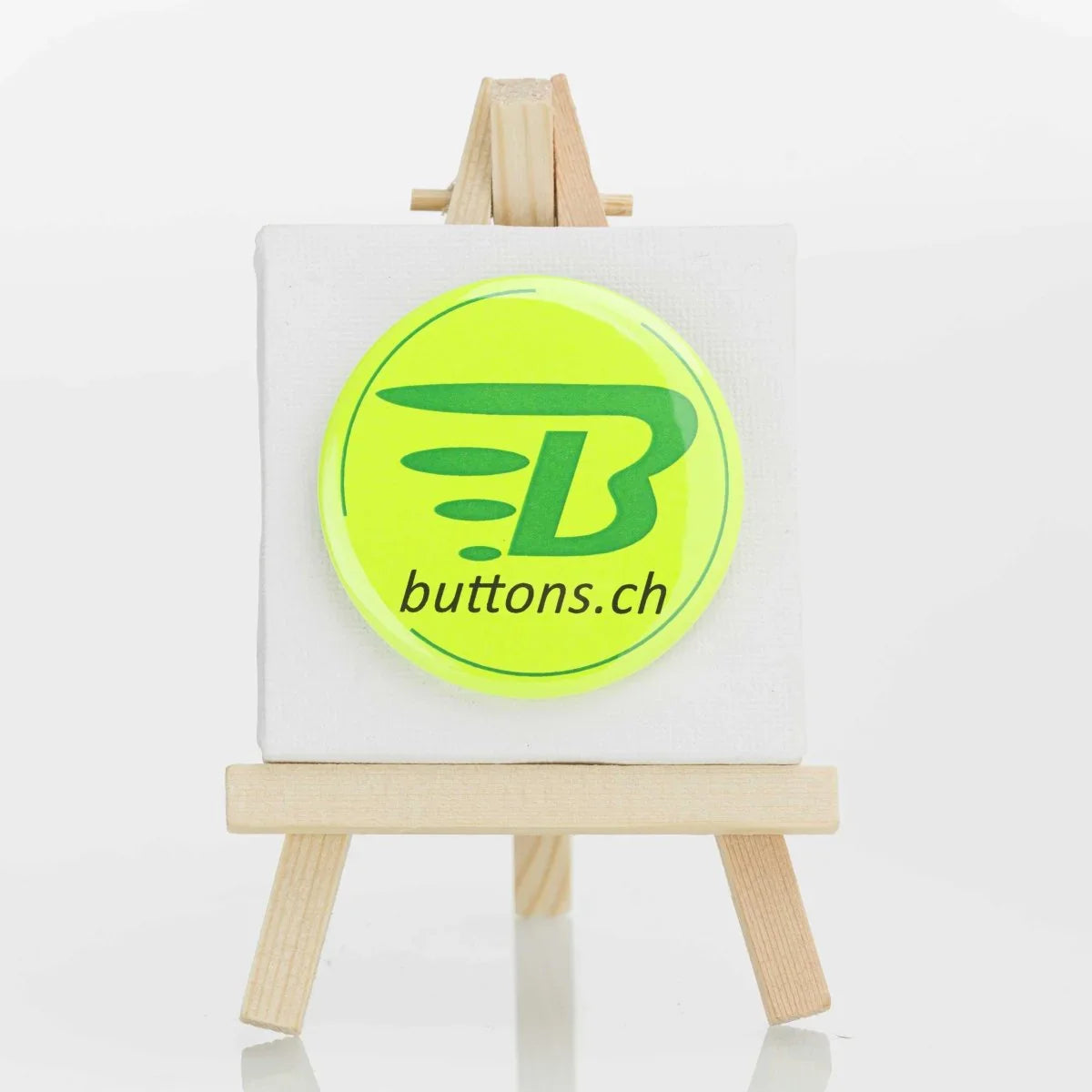 Runder Neonbutton in Neongelb, 56 mm, mit buttons.ch-Logo.