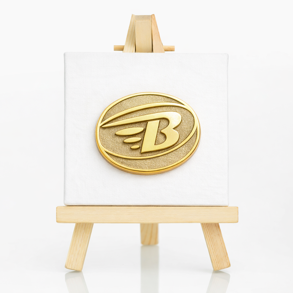 Goldener Sandstrahl-Pin mit B-Logo auf weißer Leinwand im Miniatur-Holzständer